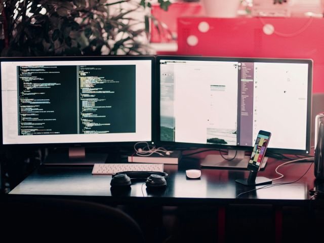 two black computer monitors on black table